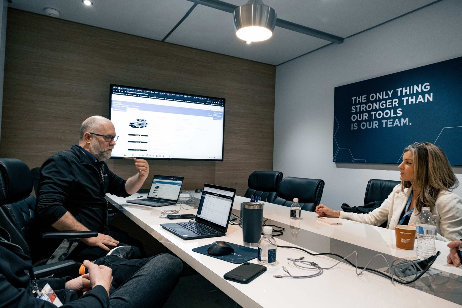 Sarah Fisher at a conference table, listening as a client talks through what is on the wall screen
